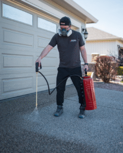 Professional applying concrete sealer to an exposed aggregate driveway in Kelowna