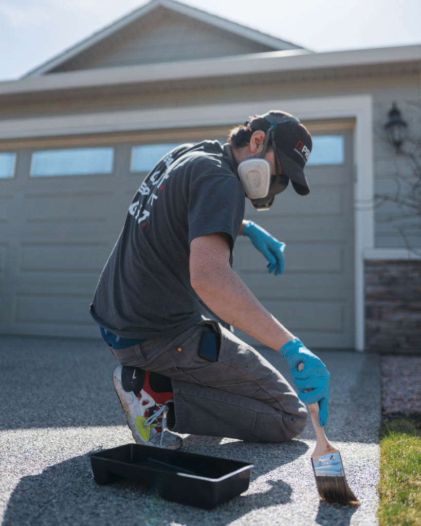 Prime team member applying concrete sealer to an exposed aggregate driveway in Kelowna