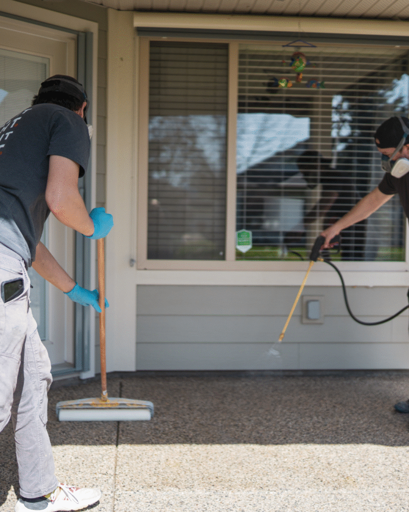 Coating technician applying concrete sealer to an exposed aggregate patio in Kelowna
