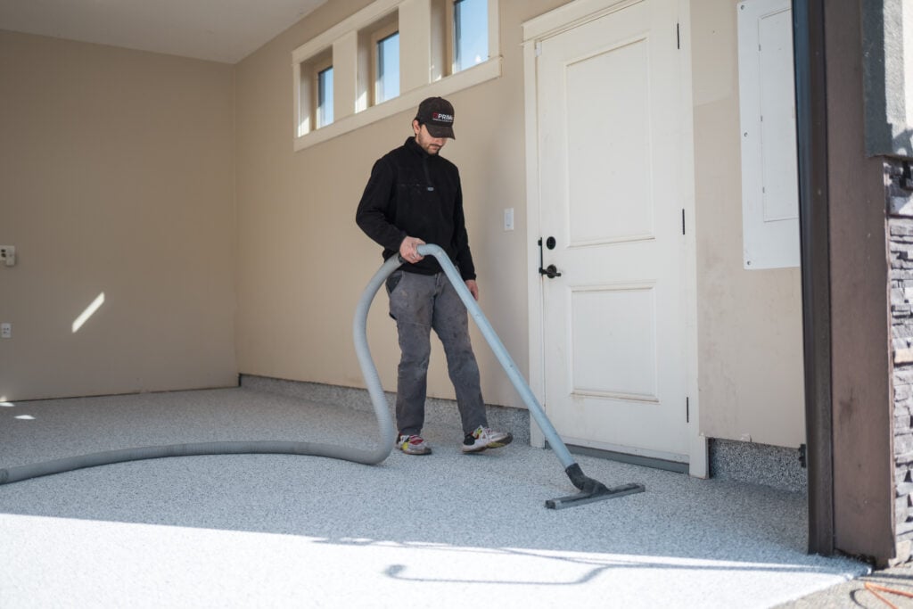 Prime Concrete Coatings team member vacuuming up flake